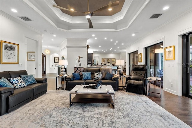 living room with hardwood / wood-style floors, a tray ceiling, ceiling fan, and ornamental molding