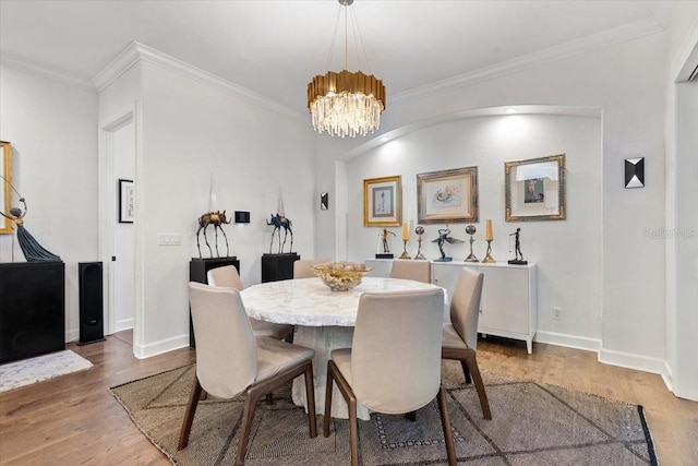 dining room with wood-type flooring, an inviting chandelier, and ornamental molding