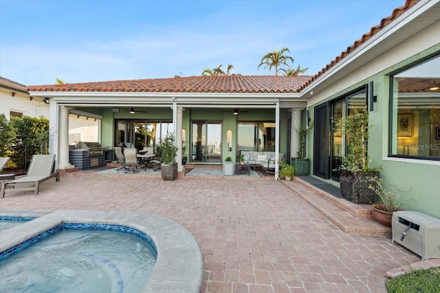 rear view of property with a hot tub, ceiling fan, and a patio area