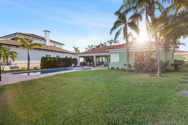 rear view of property with a fenced in pool and a yard