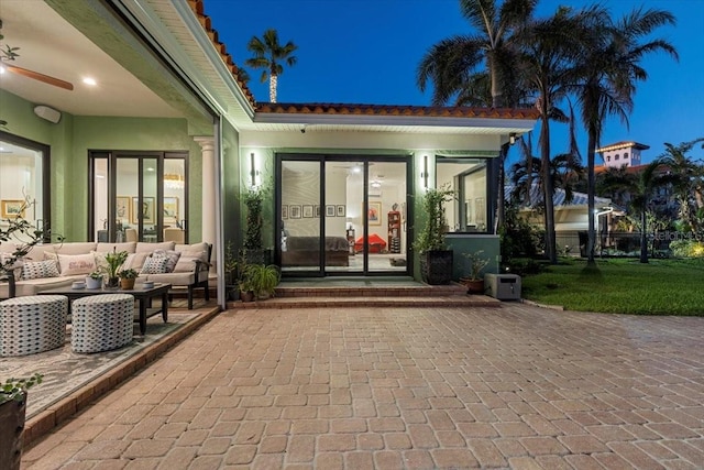 exterior entry at night featuring an outdoor living space and a patio