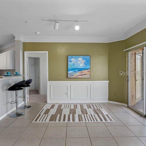 unfurnished living room with ornamental molding, rail lighting, and light tile patterned floors