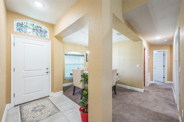 carpeted foyer with plenty of natural light and a textured ceiling