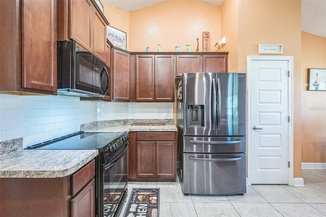 kitchen with light tile patterned flooring, decorative backsplash, vaulted ceiling, and black appliances