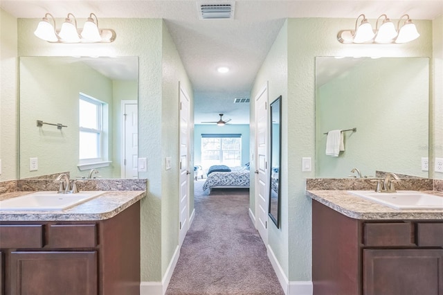 bathroom with ceiling fan, vanity, and a textured ceiling