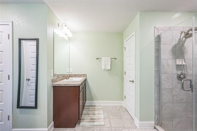 bathroom with tile patterned flooring, vanity, a shower with shower door, and a textured ceiling