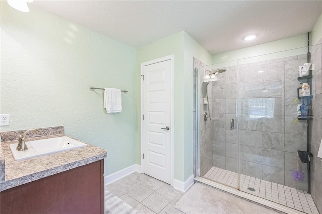 bathroom featuring tile patterned flooring, vanity, a shower with door, and a textured ceiling