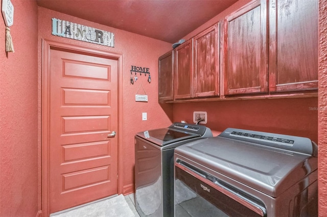 clothes washing area with washer and clothes dryer and cabinets