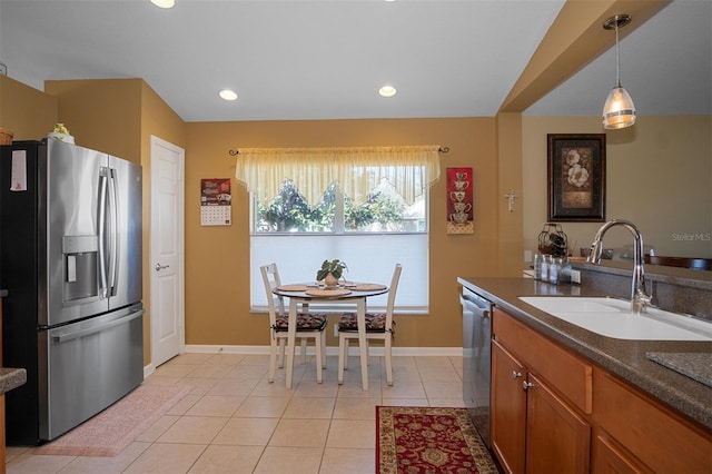 kitchen featuring sink, light tile patterned floors, hanging light fixtures, and appliances with stainless steel finishes