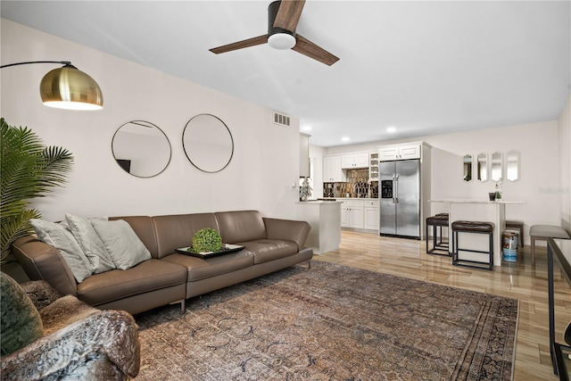 living room with ceiling fan and light hardwood / wood-style flooring