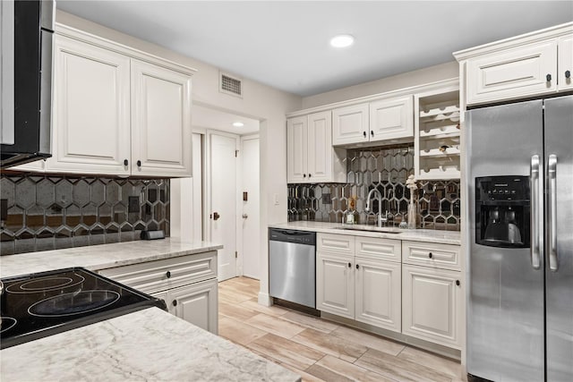 kitchen featuring appliances with stainless steel finishes, tasteful backsplash, sink, light hardwood / wood-style flooring, and white cabinetry