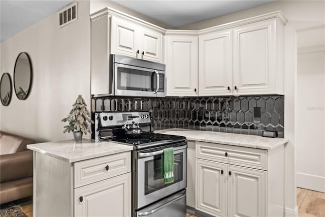 kitchen featuring appliances with stainless steel finishes, light hardwood / wood-style floors, white cabinetry, and tasteful backsplash