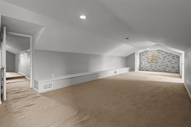 bonus room with lofted ceiling and light carpet