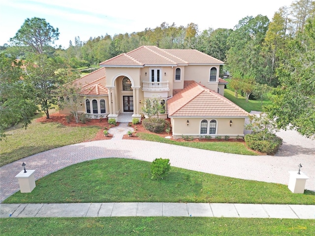 mediterranean / spanish home featuring a balcony, a front yard, and french doors