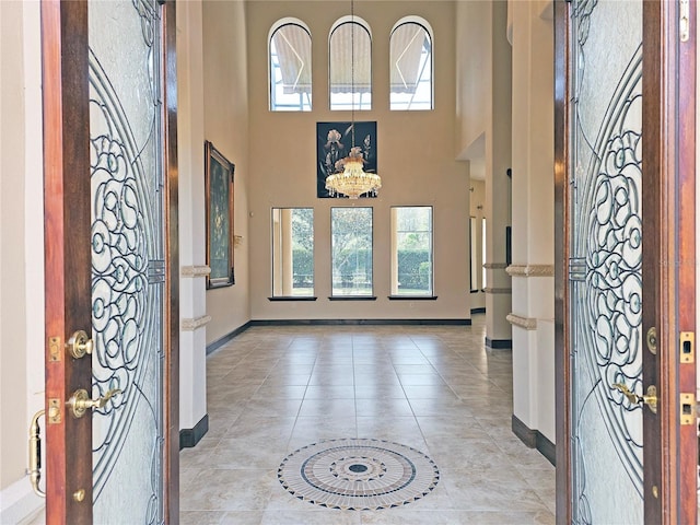 foyer with light tile patterned floors, a towering ceiling, and an inviting chandelier