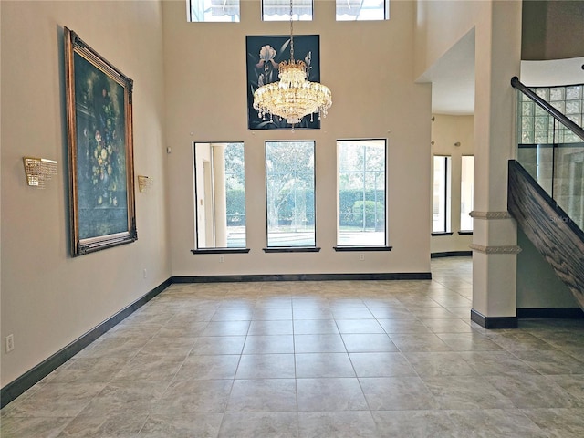 tiled entryway with a high ceiling and a notable chandelier