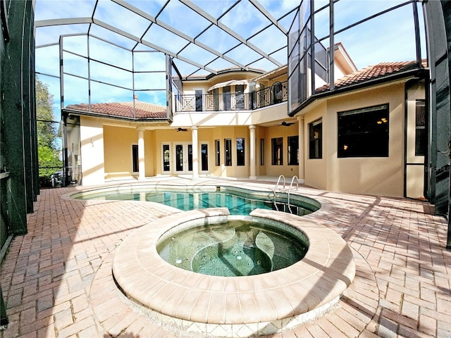 rear view of house with a lanai, a swimming pool with hot tub, a balcony, and a patio