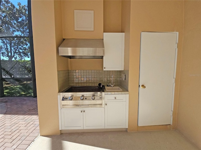 kitchen with white cabinetry, sink, wall chimney range hood, stainless steel gas stovetop, and decorative backsplash