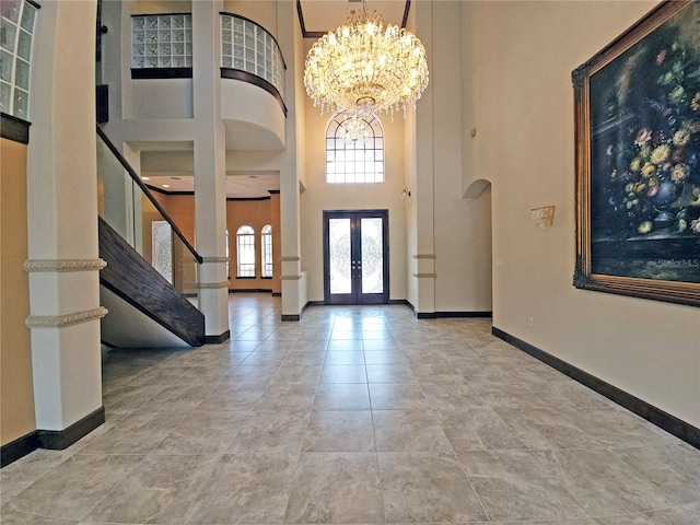 foyer entrance with a high ceiling, french doors, and a notable chandelier