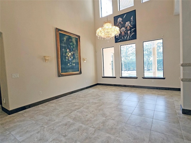 unfurnished room with a chandelier, a towering ceiling, and light tile patterned flooring