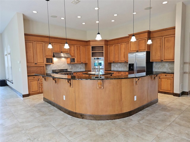 kitchen featuring appliances with stainless steel finishes, a kitchen breakfast bar, dark stone counters, a spacious island, and pendant lighting