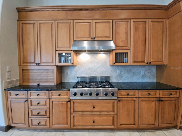 kitchen with tasteful backsplash, dark stone countertops, light tile patterned flooring, and stainless steel gas stovetop