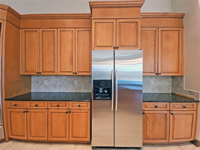 kitchen with backsplash, dark stone countertops, stainless steel fridge, and light tile patterned flooring