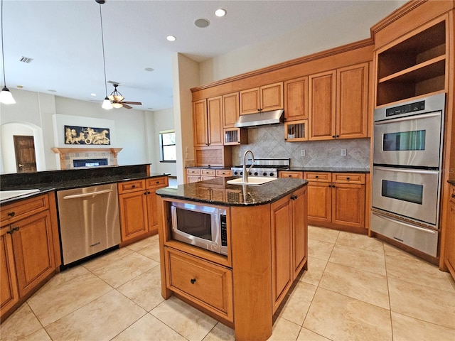 kitchen featuring appliances with stainless steel finishes, a kitchen island with sink, sink, light tile patterned floors, and decorative light fixtures