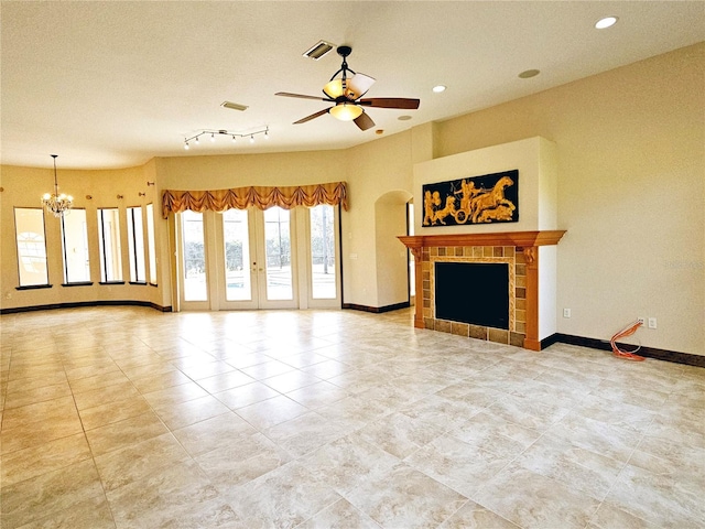 unfurnished living room with a textured ceiling, ceiling fan with notable chandelier, and a tiled fireplace