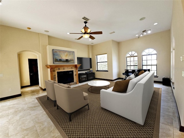 tiled living room with a tile fireplace and ceiling fan