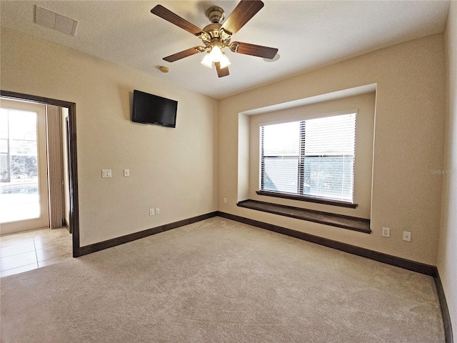 carpeted spare room with a wealth of natural light and ceiling fan