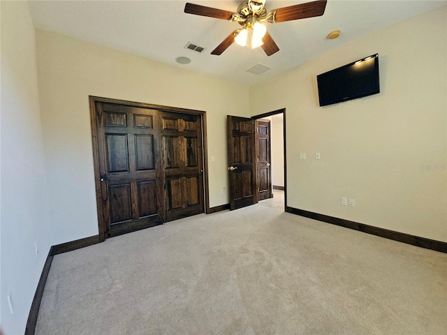 unfurnished bedroom featuring a closet, light colored carpet, and ceiling fan