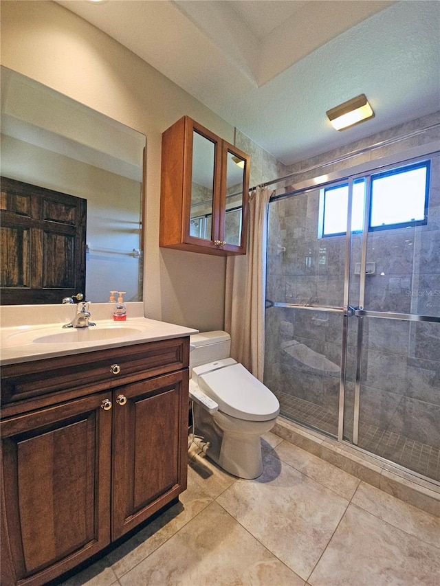 bathroom with tiled shower, tile patterned flooring, vanity, and toilet