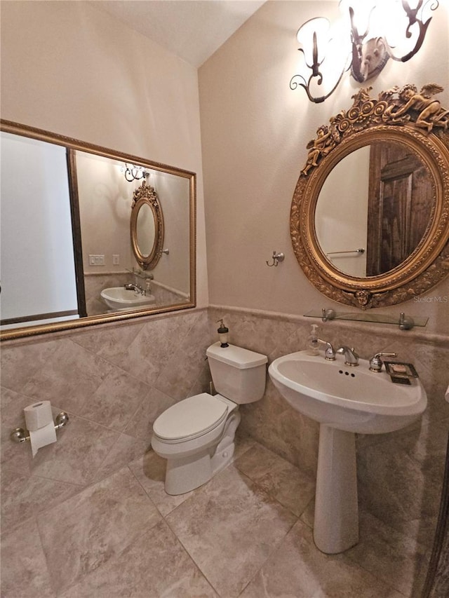 bathroom with tile patterned flooring, toilet, and tile walls