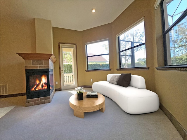 carpeted living room with a tile fireplace