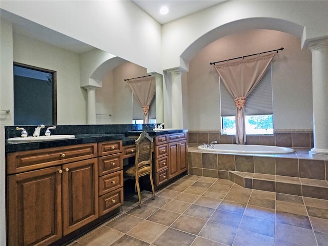 bathroom with tile patterned floors, ornate columns, vanity, and a relaxing tiled tub