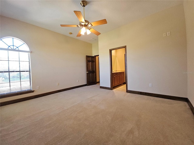 unfurnished bedroom with ceiling fan, light colored carpet, and ensuite bathroom