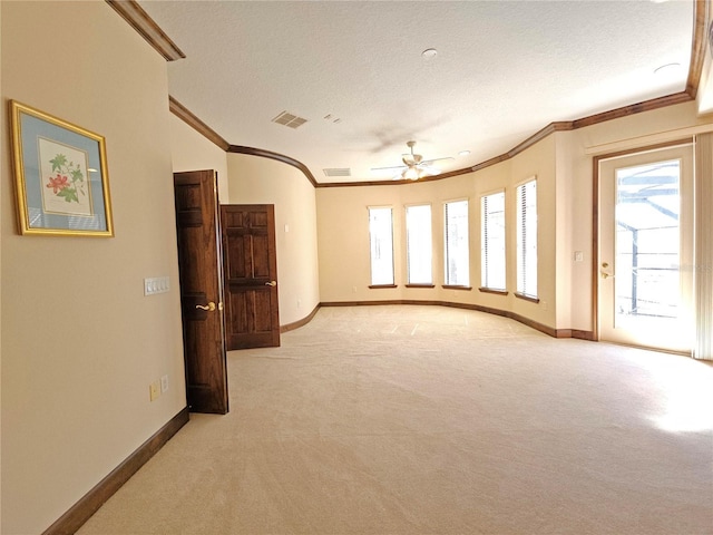 carpeted spare room featuring a textured ceiling, ceiling fan, and crown molding