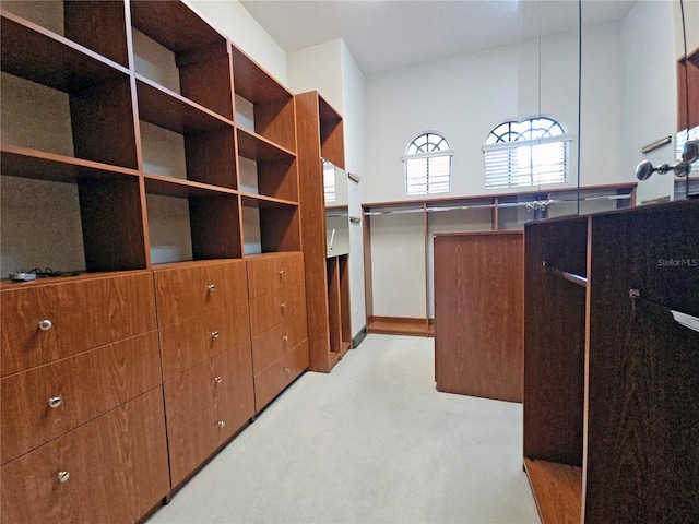 walk in closet featuring a towering ceiling and light carpet