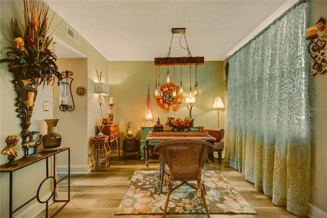 dining space featuring light wood-type flooring and a textured ceiling