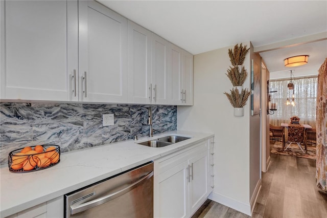 kitchen with decorative backsplash, stainless steel dishwasher, sink, white cabinets, and light hardwood / wood-style floors