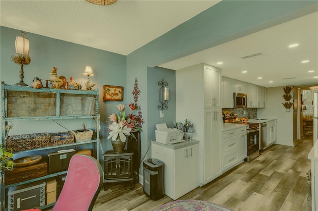 kitchen with light wood-type flooring, white cabinetry, stainless steel appliances, and tasteful backsplash