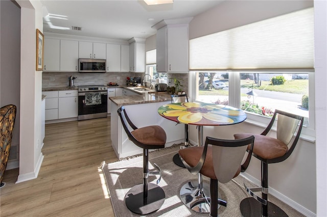 kitchen featuring sink, white cabinetry, appliances with stainless steel finishes, kitchen peninsula, and decorative backsplash