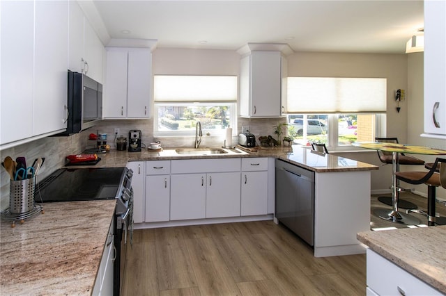 kitchen with sink, light hardwood / wood-style flooring, appliances with stainless steel finishes, white cabinetry, and decorative backsplash