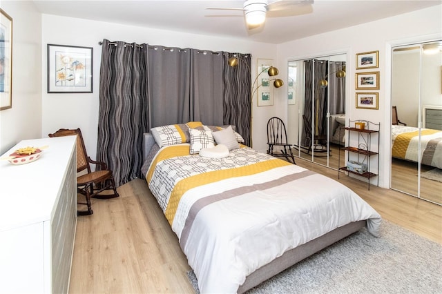 bedroom with two closets, light hardwood / wood-style flooring, and ceiling fan