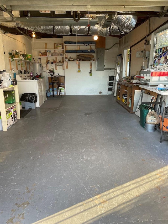 garage with water heater, washer and clothes dryer, and a workshop area