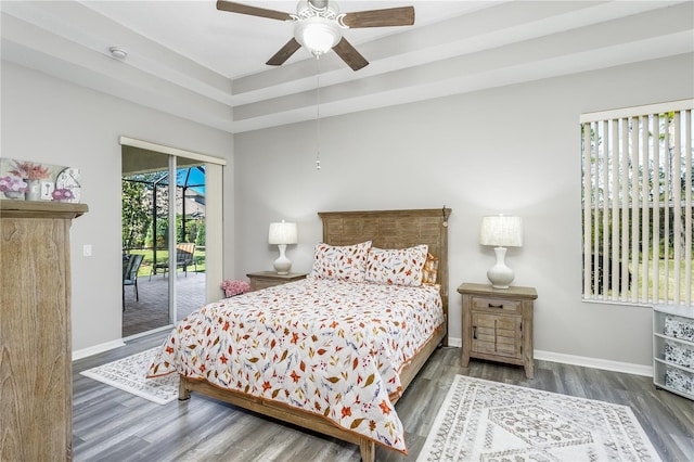 bedroom featuring dark hardwood / wood-style floors, ceiling fan, access to exterior, and a raised ceiling