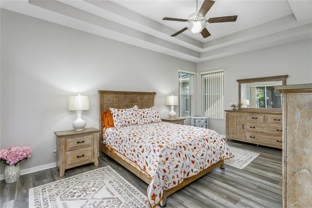 bedroom featuring dark hardwood / wood-style flooring, a raised ceiling, and ceiling fan