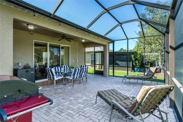 view of patio featuring a lanai, area for grilling, and ceiling fan