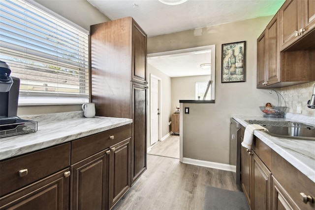 kitchen featuring sink, decorative backsplash, light stone countertops, light wood-type flooring, and dark brown cabinetry